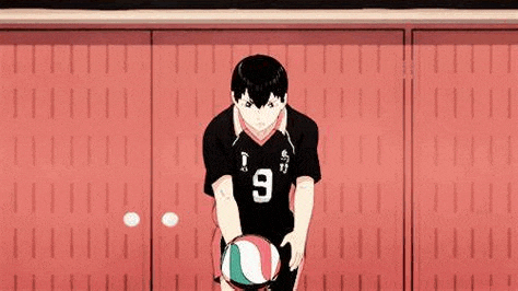 a man is holding a volleyball in his hands in front of a red wall .