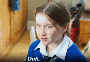 a girl in a blue shirt and tie is looking at the camera and says duh
