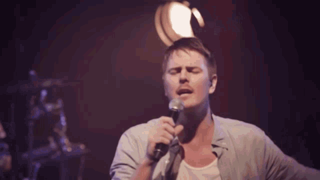 a man singing into a microphone while playing a guitar