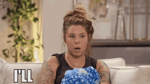 a woman is sitting on a couch with a blue blanket and the word i 'll is on the bottom right