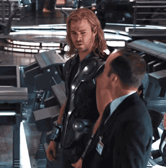 a man with a name tag that says ' chris hemsworth ' on it stands next to a man in a suit