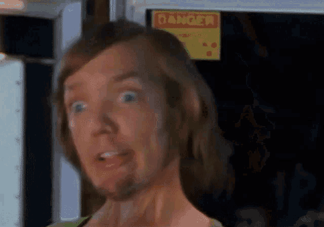 a close up of a person making a funny face in front of a danger sign .