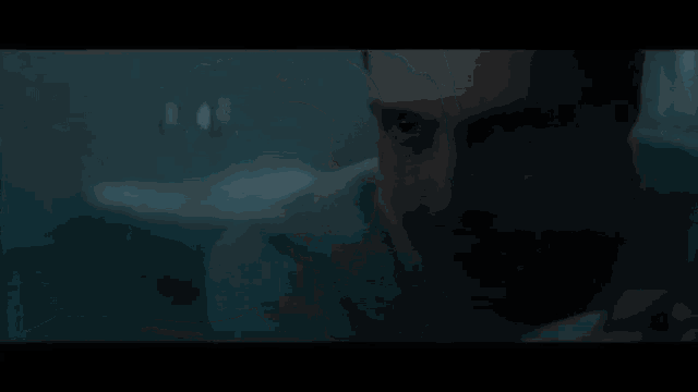 a close up of a man 's face in a dark room looking at the camera .