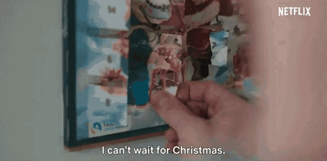 a person is holding a piece of paper in front of a picture of santa claus .