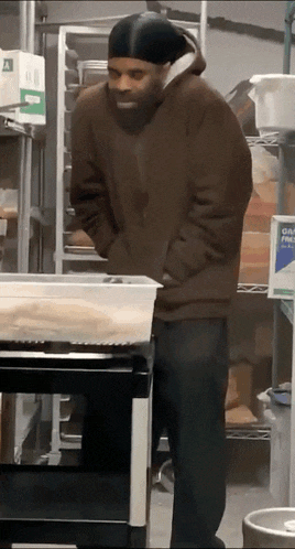 a man in a brown jacket is standing in front of a shelf with a box that says gatorade