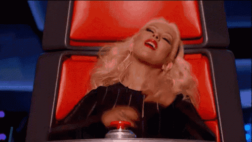 a woman is sitting in a red chair pressing a button .