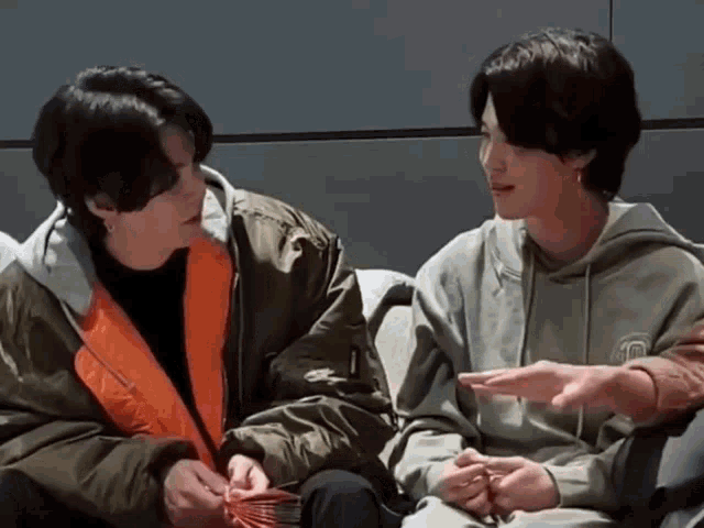 two men are sitting next to each other and talking .