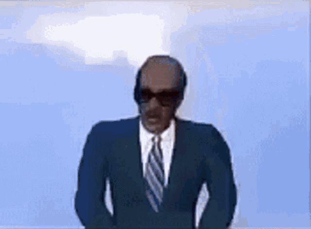 a bald man in a suit and tie wearing sunglasses .