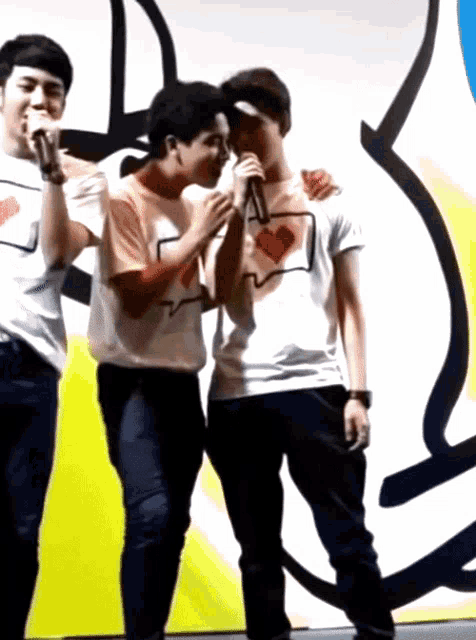 three men are standing next to each other with one wearing a shirt that says i love you