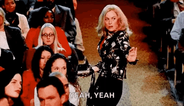 a woman is standing in front of a crowd of people and says `` yeah , yeah '' .