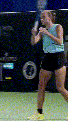 a woman in a blue tank top is swinging a tennis racquet on a tennis court