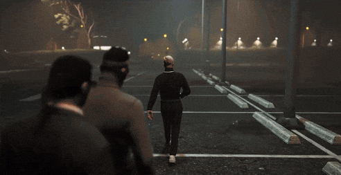 a group of men are walking down a parking lot