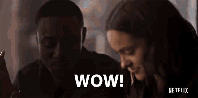 a man and a woman are sitting at a table and the man is saying wow .