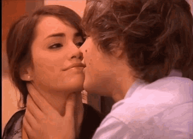 a man is kissing a woman on the cheek while holding her neck .