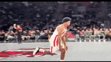a basketball player is kneeling down on the court in front of a crowd .