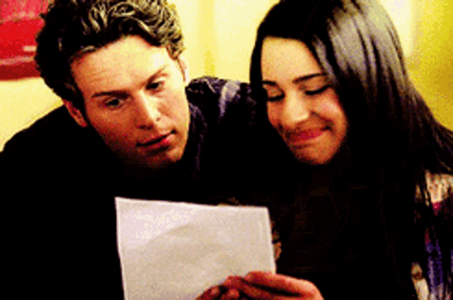 a man and woman are looking at a piece of paper together
