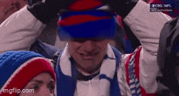 a man wearing a buffalo bills hat and scarf is crying while watching a football game .
