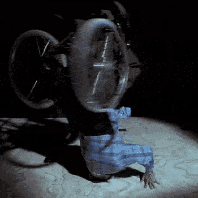a person in a plaid shirt is kneeling down in the dark holding a wheel