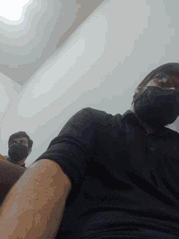 a man wearing a black shirt and a mask looks down at something