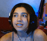 a woman wearing headphones and a necklace smiles for the camera
