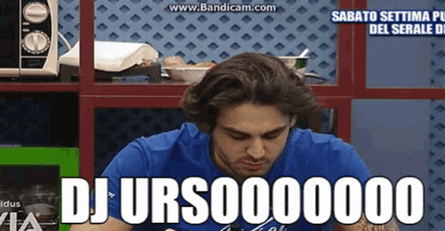 a man in a blue shirt is sitting in front of a microwave and a sign that says dj urso00000