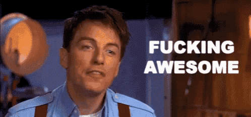a man in a blue shirt and red suspenders is saying " fucking awesome "