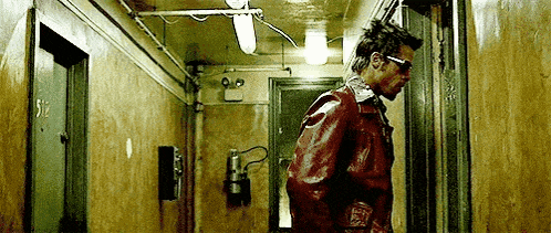 a man in a red leather jacket is standing in a dark hallway .