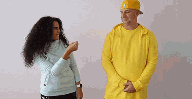a man and a woman are standing next to each other and the woman is pointing at the man