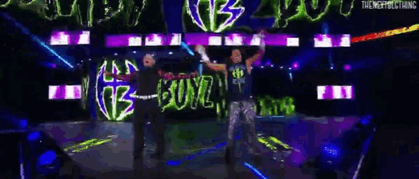 two wrestlers are standing on a stage in front of a neon sign that says bad boyz .
