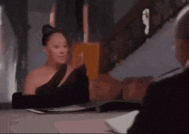 a woman in a black dress is sitting at a table