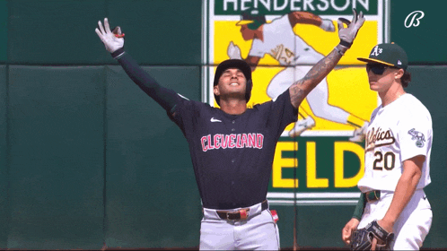 a baseball player for the cleveland indians stands in front of a wall