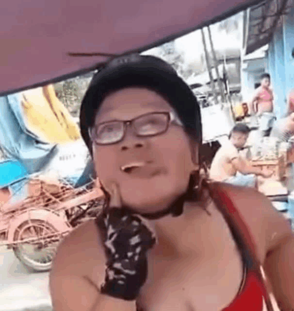 a woman wearing a helmet and glasses is making a funny face while standing on a street .