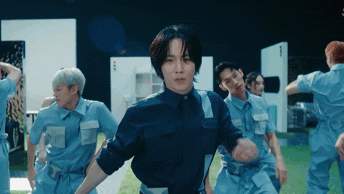 a group of men in blue uniforms are dancing together