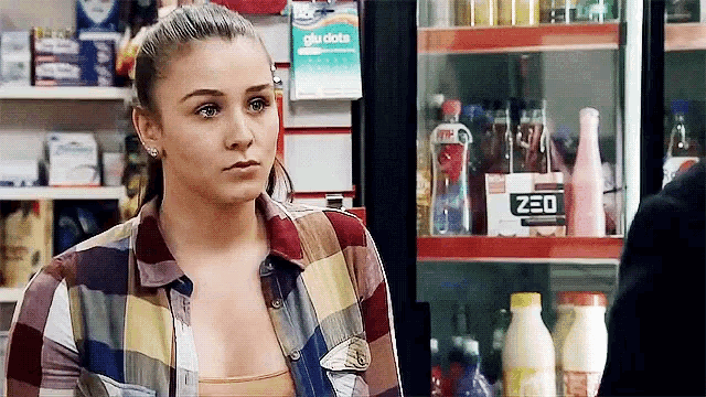 a woman in a plaid shirt is standing in front of a fridge that says zeo on it .
