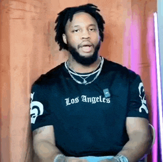 a man with a beard is wearing a los angeles t-shirt and necklaces .