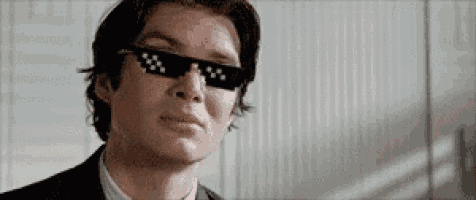 a man in a suit and tie is wearing sunglasses and making a funny face .