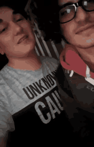 two men are posing for a picture and one of them is wearing an unknown cat t-shirt .