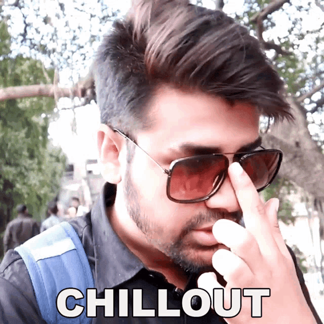a man wearing sunglasses is covering his nose with his finger and the word chillout is above him