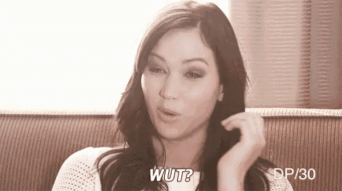 a woman is sitting on a couch making a funny face and asking wut .