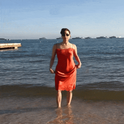 a woman in a red dress stands in the ocean