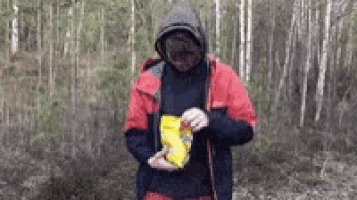 a man in a red jacket is holding a bag of chips