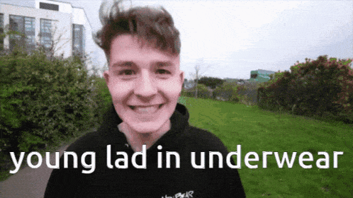 a young man wearing a black hoodie is smiling with the words young lad in underwear below him