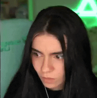 a woman with long black hair is making a funny face .