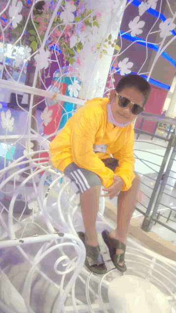 a boy wearing sunglasses and a yellow jacket sits on a chair