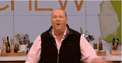 a man in a pink shirt and black vest is standing in front of a wall that says ctv