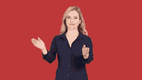 a woman wearing a blue shirt and a necklace is clapping her hands