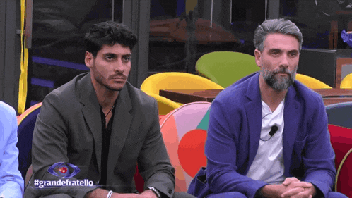 two men are sitting next to each other with the words grandefratello on the screen