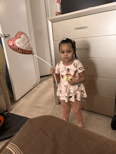 a little girl is holding a heart shaped balloon that says " happy valentine 's day "
