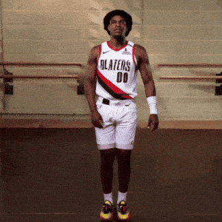 a man wearing a blazers jersey and shorts jumps in the air