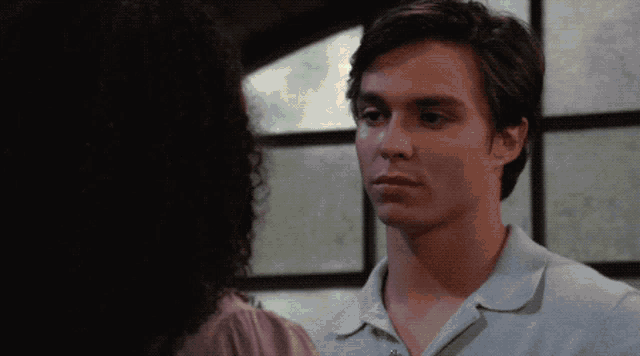 a man and woman are looking at each other and the man is wearing a blue shirt